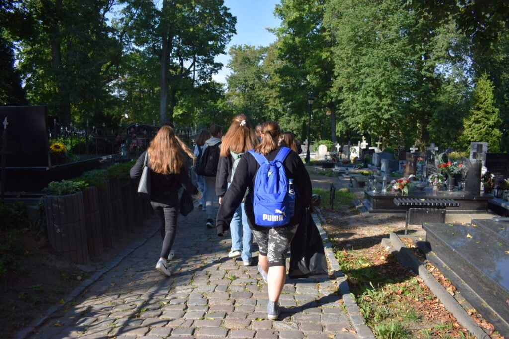 grupa uczniów na cmentarzu podczas akcji sprzątania świata