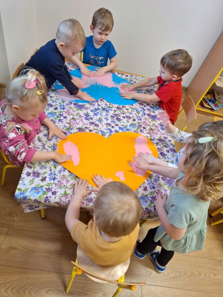 dzieci kolorują wycięte duże serce z papieru