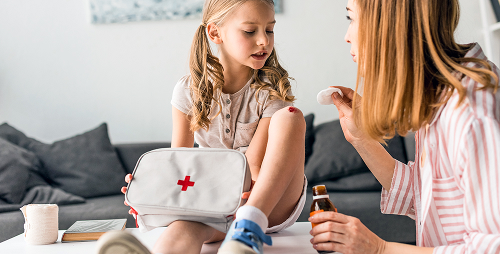 mama opatruje ranę na kolanie swojej córki przy użyciu wyposażenia apteczki domowej